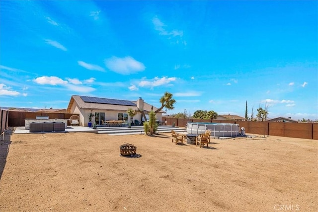 3715 Surrey, Yucca Valley, CA 92284 - rear view of house featuring a fire pit, solar panels, a fenced backyard, and a patio area
