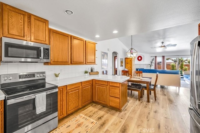 3715 Surrey, Yucca Valley, CA 92284 - kitchen with appliances with stainless steel finishes, arched walkways, light wood-type flooring, a peninsula, and backsplash