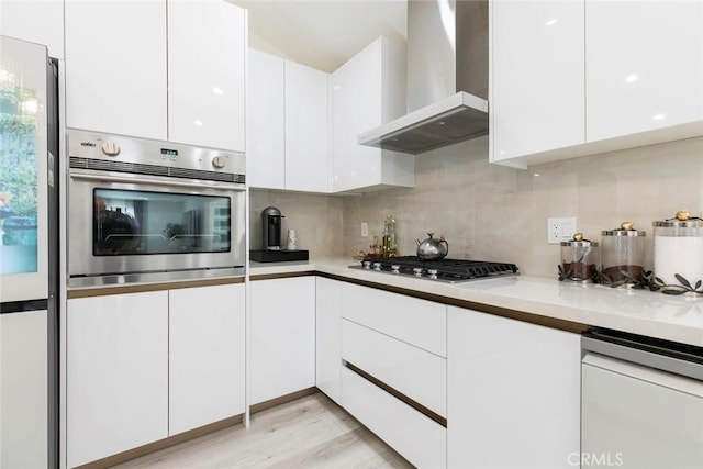 23500 Lloyd Houghton Pl, Newhall, CA 91321 - kitchen featuring wall chimney range hood, appliances with stainless steel finishes, modern cabinets, backsplash, and white cabinetry