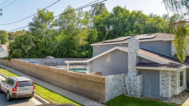 23500 Lloyd Houghton Pl, Newhall, CA 91321 - view of property exterior with stucco siding, solar panels, a chimney, and stone siding
