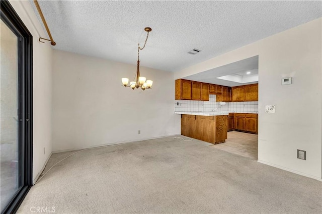 204 Hawk Ln, Palmdale, CA 93551 - kitchen featuring brown cabinetry, a peninsula, a chandelier, light carpet, and a raised ceiling