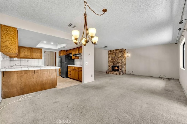 204 Hawk Ln, Palmdale, CA 93551 - kitchen with freestanding refrigerator, brown cabinetry, open floor plan, tile counters, and a peninsula