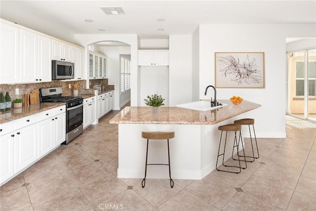 967 Strawberry Creek St, Chula Vista, CA 91913 - kitchen featuring appliances with stainless steel finishes, decorative backsplash, light stone countertops, a kitchen bar, and recessed lighting