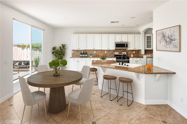 967 Strawberry Creek St, Chula Vista, CA 91913 - kitchen featuring stainless steel microwave, tasteful backsplash, a breakfast bar, and white cabinets