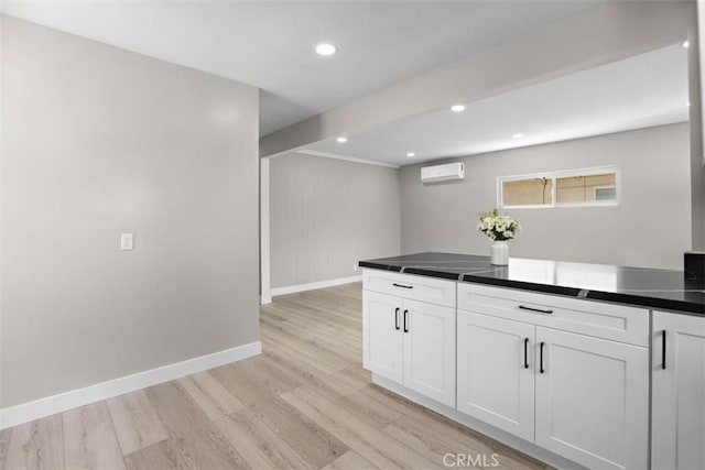 5021 Harbor St, Commerce, CA 90040 - kitchen featuring light wood finished floors, dark countertops, an AC wall unit, white cabinets, and recessed lighting
