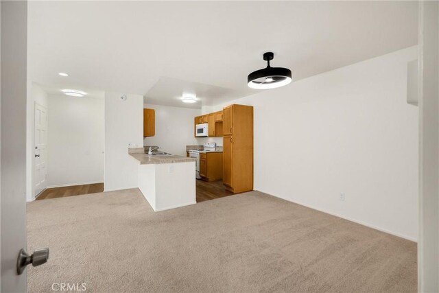 2521 W Sunflower Ave Unit R8, Santa Ana, CA 92704 - kitchen featuring white appliances, dark carpet, a peninsula, light countertops, and brown cabinetry
