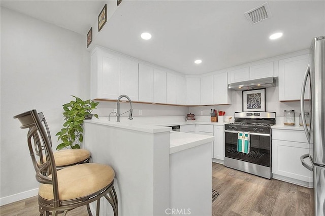 1068 Border Ave, Corona, CA 92882 - kitchen with appliances with stainless steel finishes, under cabinet range hood, a peninsula, white cabinets, and light wood-style flooring
