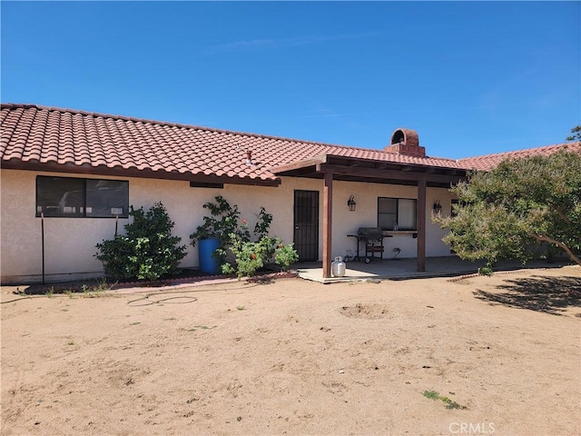 15440 Cactus St, Hesperia, CA 92345 - rear view of house featuring stucco siding, a tile roof, and a chimney