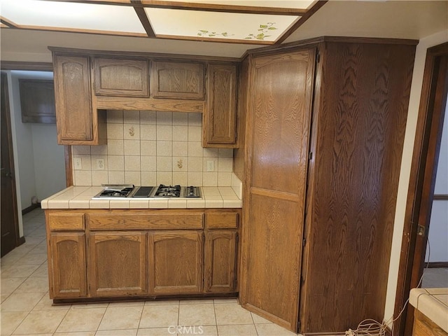 15440 Cactus St, Hesperia, CA 92345 - kitchen featuring stainless steel gas stovetop, tile countertops, tasteful backsplash, and light tile patterned floors