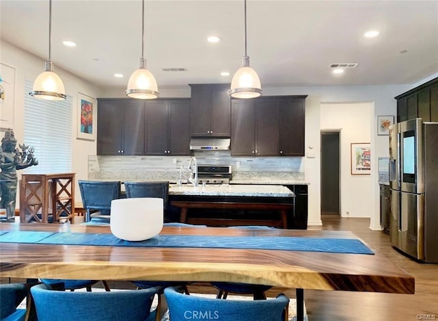 28667 Clearview St, Murrieta, CA 92563 - kitchen with stainless steel fridge, under cabinet range hood, stove, backsplash, and pendant lighting