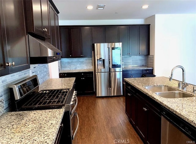 28667 Clearview St, Murrieta, CA 92563 - kitchen featuring appliances with stainless steel finishes, under cabinet range hood, light stone countertops, dark wood-type flooring, and decorative backsplash