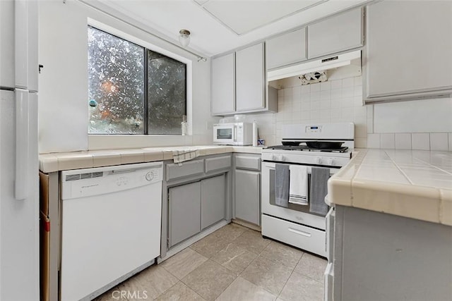 1553 Dennis Pl, West Covina, CA 91790 - kitchen with white appliances, tile counters, under cabinet range hood, and gray cabinetry