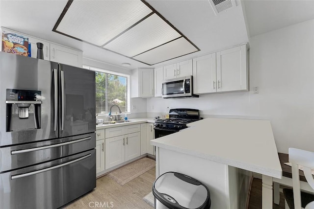 1553 Dennis Pl, West Covina, CA 91790 - kitchen with stainless steel appliances, a peninsula, light wood-style flooring, and white cabinetry