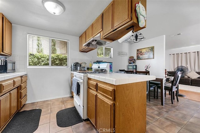 1553 Dennis Pl, West Covina, CA 91790 - kitchen featuring white gas stove, tile countertops, under cabinet range hood, open floor plan, and light tile patterned floors