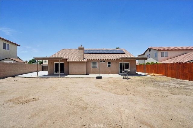 12671 Shorewood Ln, Victorville, CA 92392 - back of house featuring a patio, a chimney, stucco siding, a fenced backyard, and roof mounted solar panels