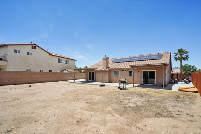 12671 Shorewood Ln, Victorville, CA 92392 - rear view of property with roof mounted solar panels, a patio, a chimney, a fenced backyard, and a tile roof