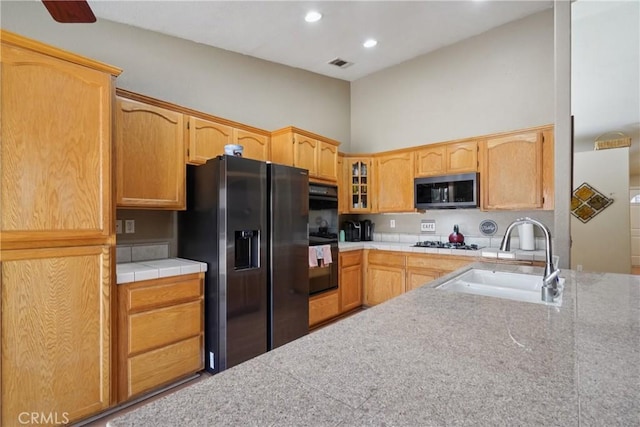 12671 Shorewood Ln, Victorville, CA 92392 - kitchen featuring refrigerator with ice dispenser, stainless steel microwave, gas cooktop, glass insert cabinets, and a high ceiling