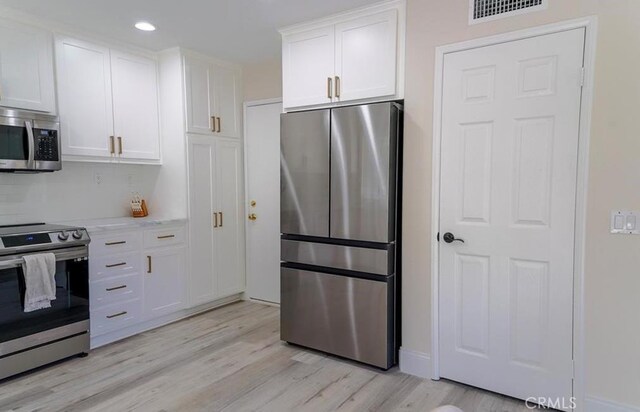 15 Parisville, Aliso Viejo, CA 92656 - kitchen featuring stainless steel appliances, white cabinetry, light wood finished floors, backsplash, and recessed lighting
