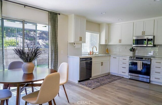 15 Parisville, Aliso Viejo, CA 92656 - kitchen featuring appliances with stainless steel finishes, light countertops, tasteful backsplash, light wood-type flooring, and white cabinets