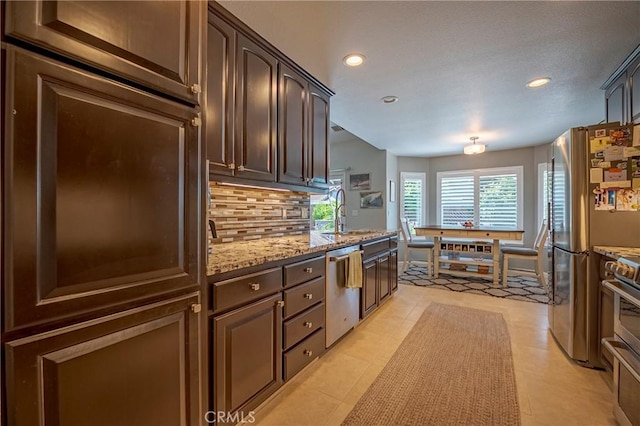 3486 Cascade Creek Ave, Merced, CA 95340 - kitchen with appliances with stainless steel finishes, decorative backsplash, light stone countertops, recessed lighting, and dark brown cabinetry