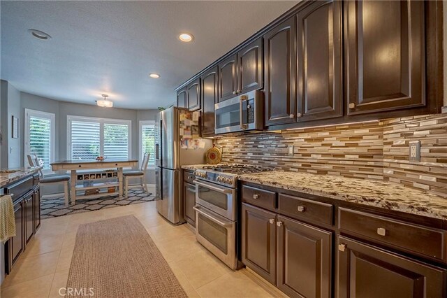 3486 Cascade Creek Ave, Merced, CA 95340 - kitchen featuring stainless steel appliances, dark brown cabinetry, backsplash, light stone countertops, and recessed lighting