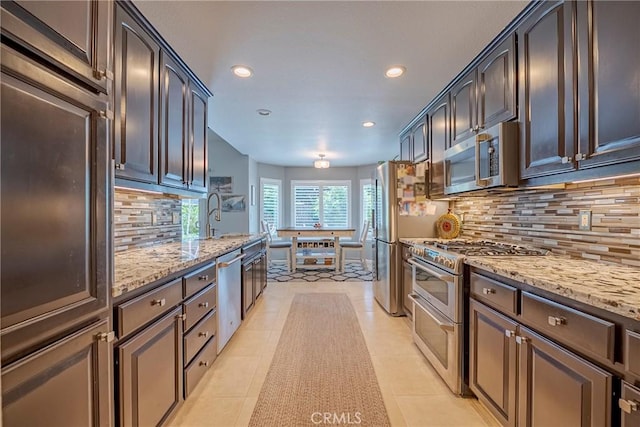 3486 Cascade Creek Ave, Merced, CA 95340 - kitchen with appliances with stainless steel finishes, light stone counters, recessed lighting, tasteful backsplash, and dark brown cabinetry