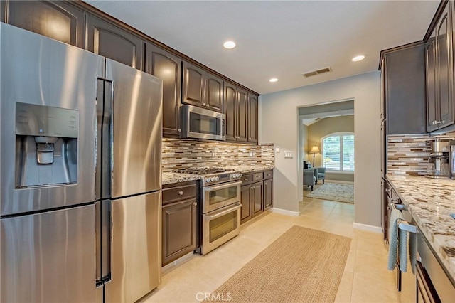 3486 Cascade Creek Ave, Merced, CA 95340 - kitchen featuring appliances with stainless steel finishes, backsplash, recessed lighting, dark brown cabinetry, and light stone counters