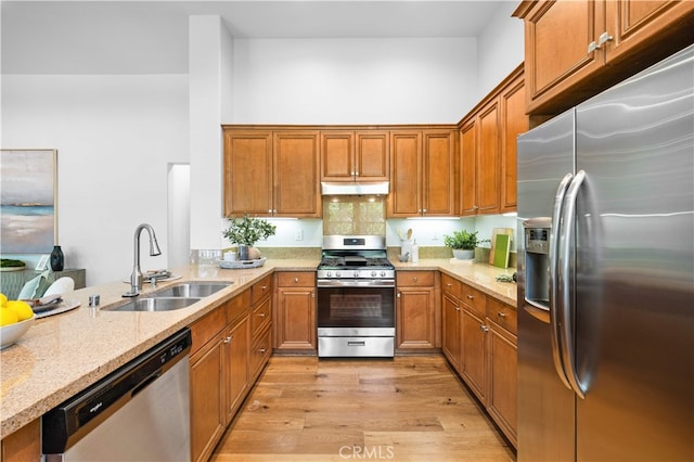 83 City Stroll, Irvine, CA 92620 - kitchen with stainless steel appliances, under cabinet range hood, brown cabinetry, light wood finished floors, and a towering ceiling