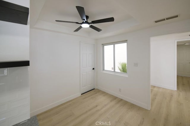14163 Wimbleton Dr, Victorville, CA 92395 - spare room featuring a tray ceiling, light wood-type flooring, and a ceiling fan