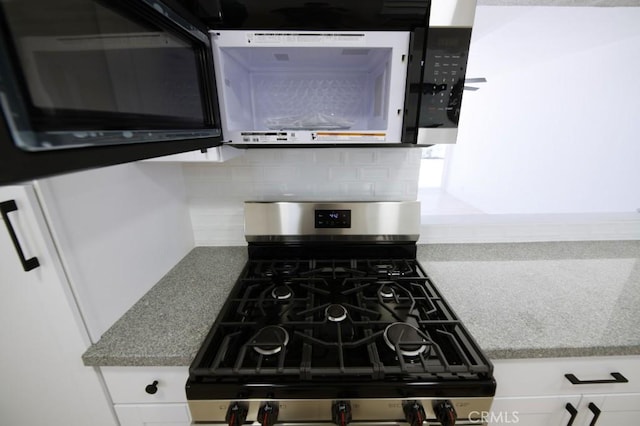 14163 Wimbleton Dr, Victorville, CA 92395 - kitchen view of stainless steel gas range oven, backsplash, black microwave, and white cabinets