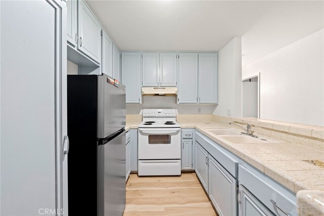 4647 Pico St Unit 101, San Diego, CA 92109 - kitchen with freestanding refrigerator, white electric stove, under cabinet range hood, light wood-type flooring, and gray cabinets