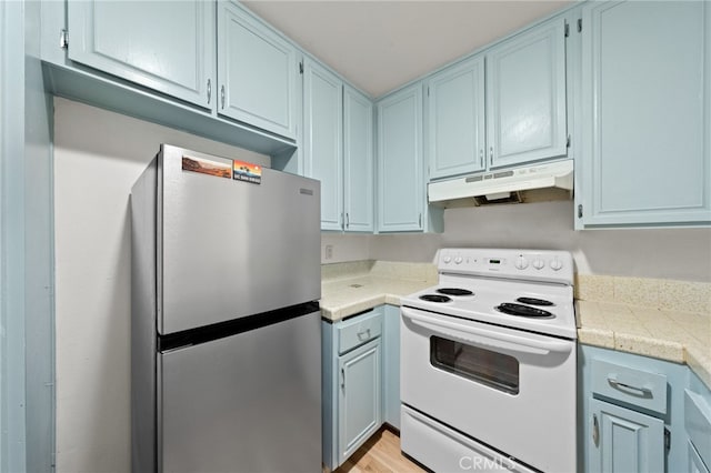 4647 Pico St Unit 101, San Diego, CA 92109 - kitchen with freestanding refrigerator, electric range, under cabinet range hood, and blue cabinetry