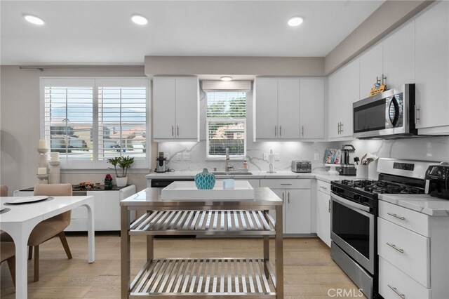 10554 Cannon Dr, Rancho Cucamonga, CA 91730 - kitchen featuring stainless steel appliances, light wood finished floors, light countertops, tasteful backsplash, and white cabinetry