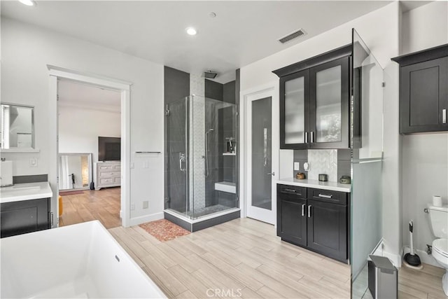 949 Moody Pl, Claremont, CA 91711 - full bathroom with a stall shower, a freestanding tub, wood finished floors, recessed lighting, and vanity