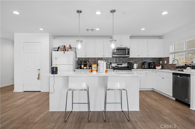 20225 Breeze Blooms Dr, Riverside, CA 92507 - kitchen with appliances with stainless steel finishes, a center island, decorative backsplash, white cabinets, and a kitchen breakfast bar