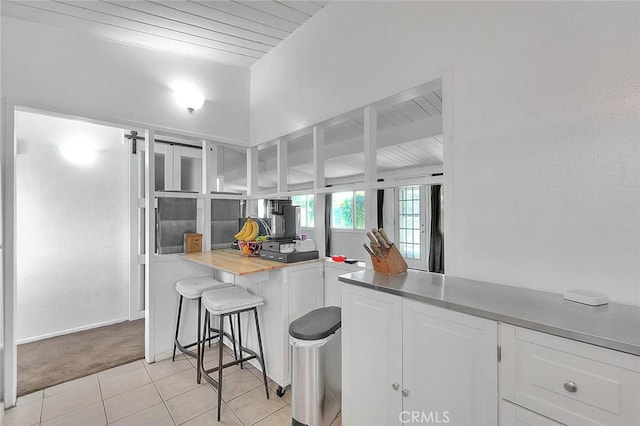 17109 E Orkney St, Azusa, CA 91702 - kitchen featuring white cabinetry, wood ceiling, light tile patterned floors, a breakfast bar, and a barn door
