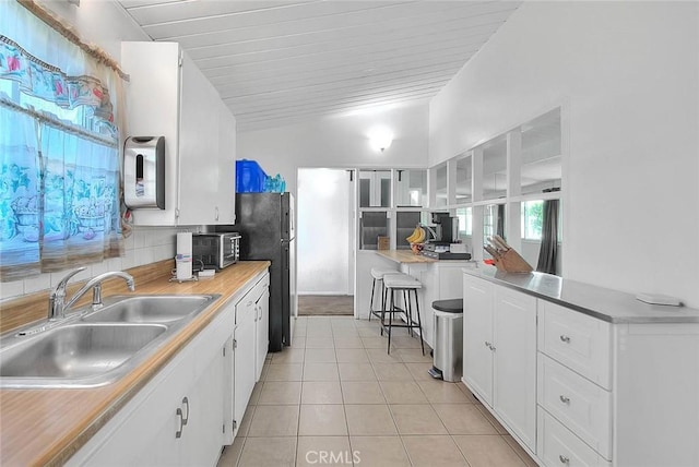 17109 E Orkney St, Azusa, CA 91702 - kitchen featuring light tile patterned flooring, white cabinets, vaulted ceiling, freestanding refrigerator, and light countertops