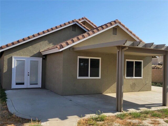 955 Mill Iron Way, San Jacinto, CA 92583 - back of property with french doors, stucco siding, a patio, and a tile roof