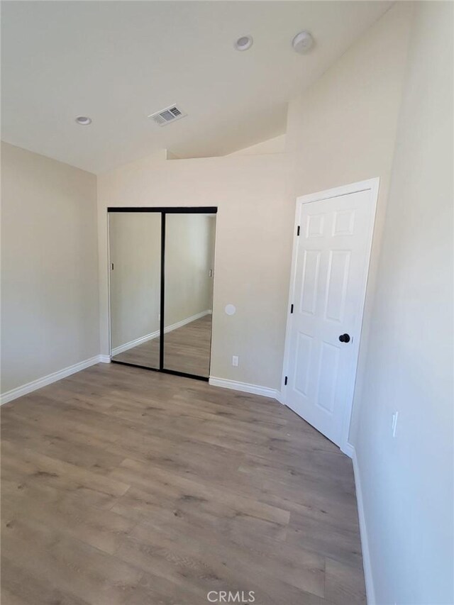 955 Mill Iron Way, San Jacinto, CA 92583 - unfurnished bedroom featuring vaulted ceiling, wood finished floors, a closet, and recessed lighting