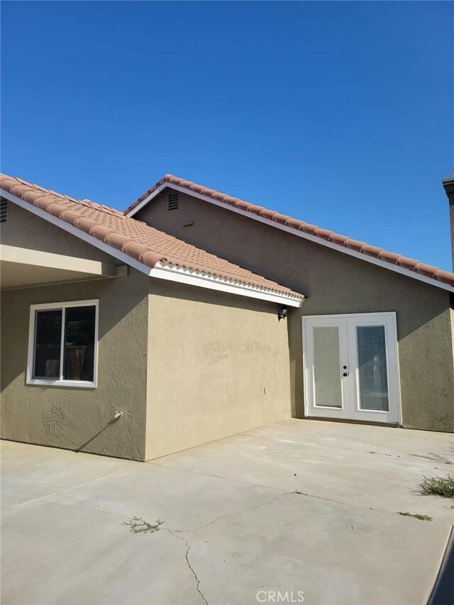 955 Mill Iron Way, San Jacinto, CA 92583 - view of side of home with a patio, stucco siding, french doors, and a tiled roof