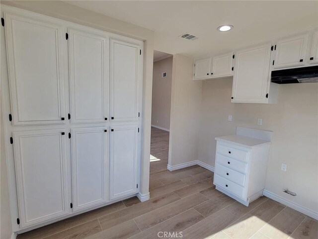955 Mill Iron Way, San Jacinto, CA 92583 - kitchen featuring under cabinet range hood, wood finish floors, white cabinetry, recessed lighting, and light countertops