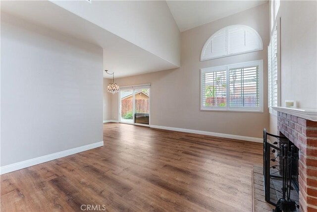 2547 Orange Ave Unit D, Costa Mesa, CA 92627 - unfurnished living room with a chandelier, a brick fireplace, wood finished floors, and lofted ceiling