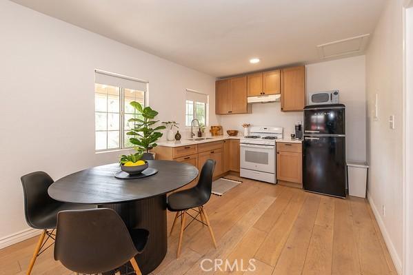 1186 Buelah Ave, City Terrace, CA 90063 - kitchen with freestanding refrigerator, white range with gas stovetop, under cabinet range hood, stainless steel microwave, and light wood-style floors