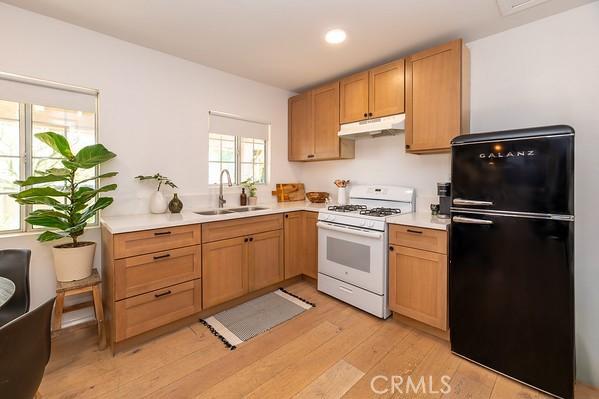 1186 Buelah Ave, City Terrace, CA 90063 - kitchen with freestanding refrigerator, white gas range, under cabinet range hood, light wood-type flooring, and light countertops