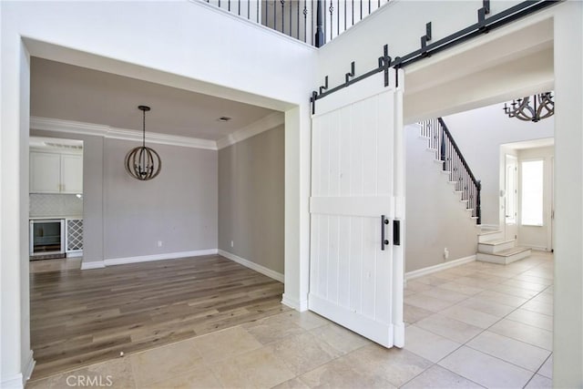 45118 Riverstone Ct, Temecula, CA 92592 - unfurnished living room featuring a barn door, a chandelier, crown molding, stairway, and light tile patterned floors