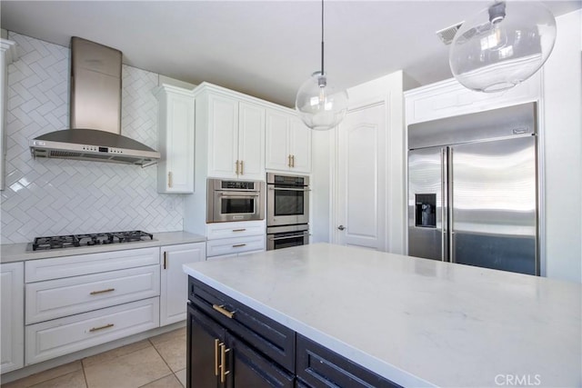 45118 Riverstone Ct, Temecula, CA 92592 - kitchen with appliances with stainless steel finishes, wall chimney exhaust hood, white cabinets, decorative backsplash, and light tile patterned floors