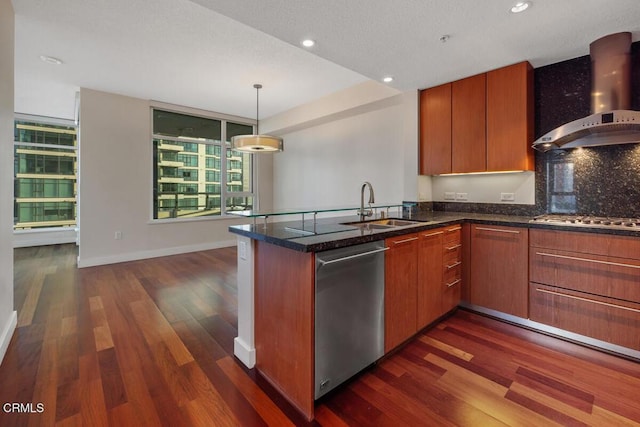 1205 Pacific Hwy Unit 1005, San Diego, CA 92101 - kitchen featuring wall chimney exhaust hood, appliances with stainless steel finishes, a peninsula, dark wood finished floors, and dark stone counters