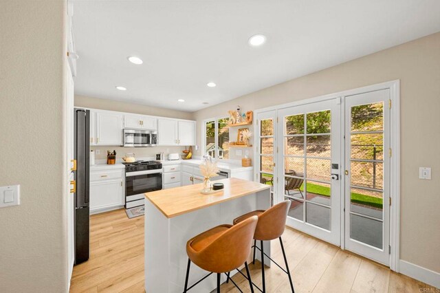 641 Hillhaven Dr, San Marcos, CA 92078 - kitchen with appliances with stainless steel finishes, white cabinetry, healthy amount of natural light, a kitchen breakfast bar, and recessed lighting