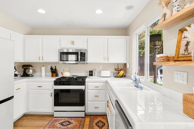 641 Hillhaven Dr, San Marcos, CA 92078 - kitchen with appliances with stainless steel finishes, tile counters, white cabinets, light wood-style flooring, and recessed lighting