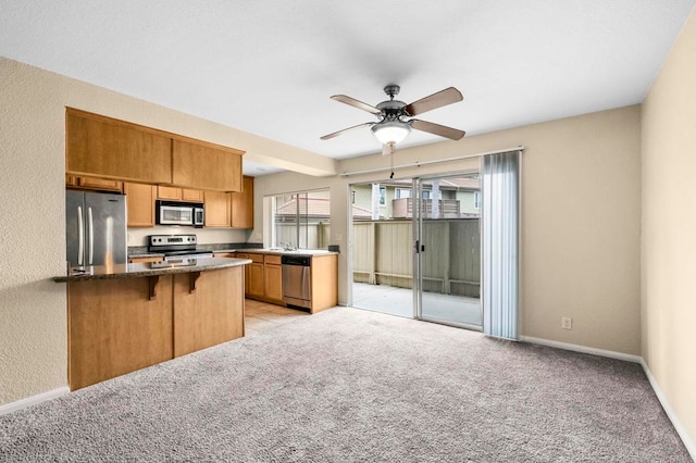 615 Fredricks Ave Unit 103, Oceanside, CA 92058 - kitchen with stainless steel appliances, a breakfast bar, light colored carpet, a ceiling fan, and a textured wall